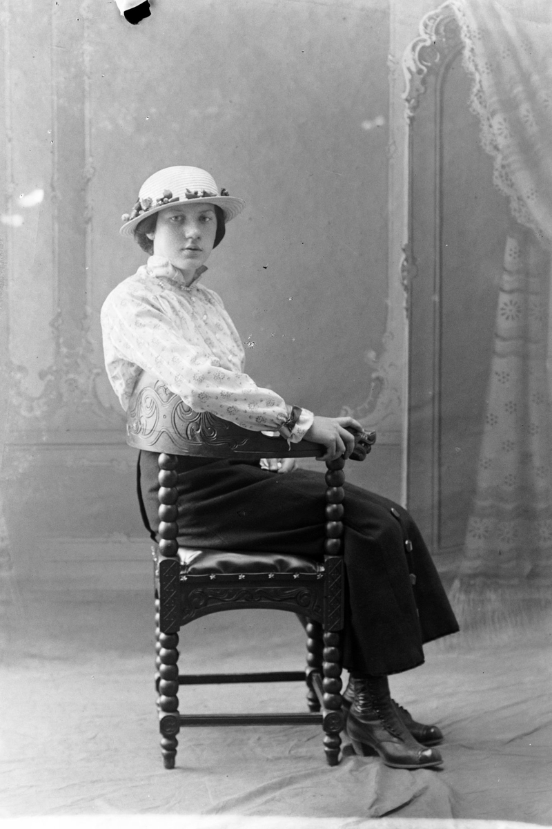 Studioportrett av en kvinne sittende på en stol.