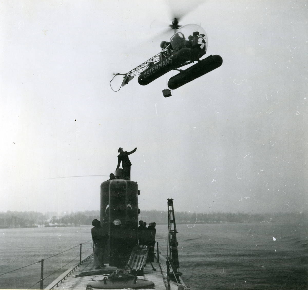 Helikopter fotograferad när den firar ner reservdelar till en ubåt.