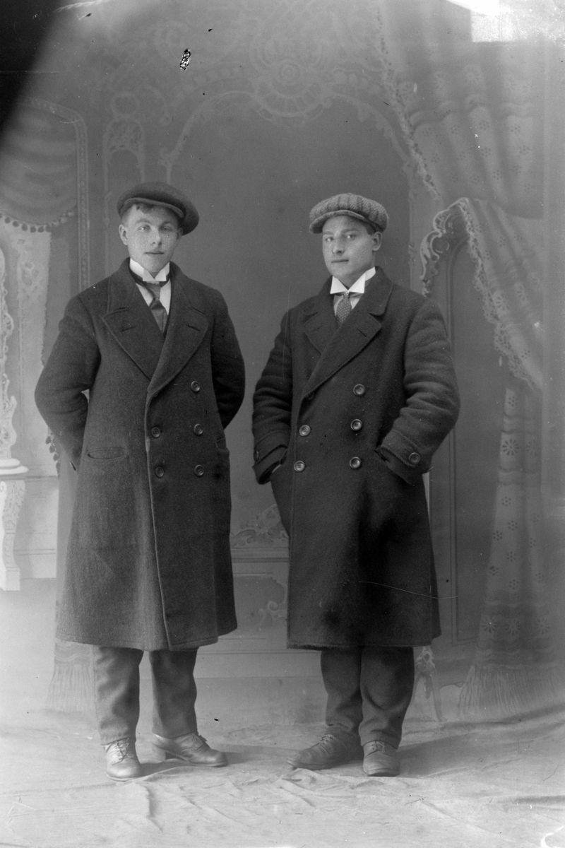 Studioportrett av to menn kledd i frakker.