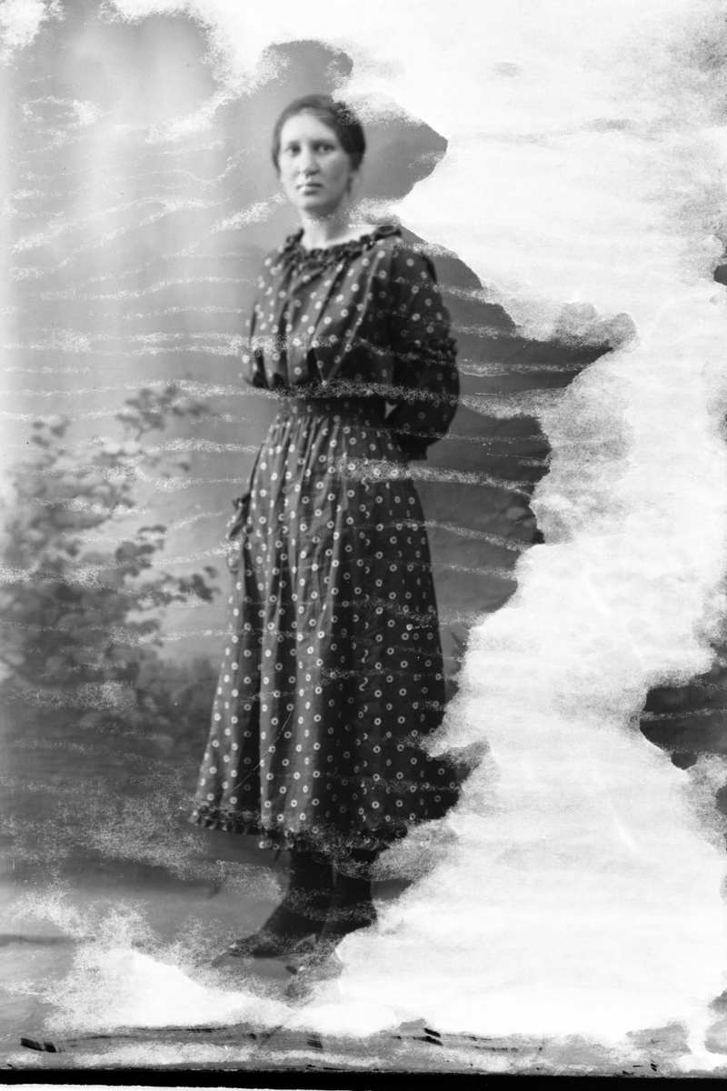 Studioportrett av en kvinne kledd i en prikket kjole.