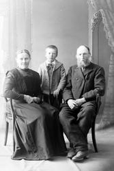 Studioportrett av et eldre par med et barn.