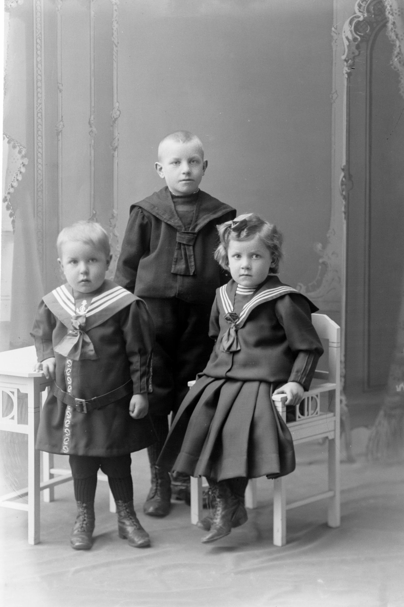 Studioportrett av tre barn, to av dem kledd i matrosdresser.