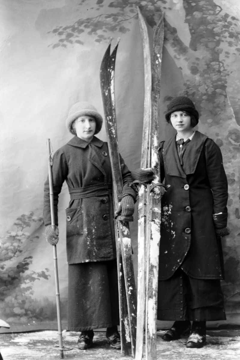 Studioportrett av to kvinner med ski.
