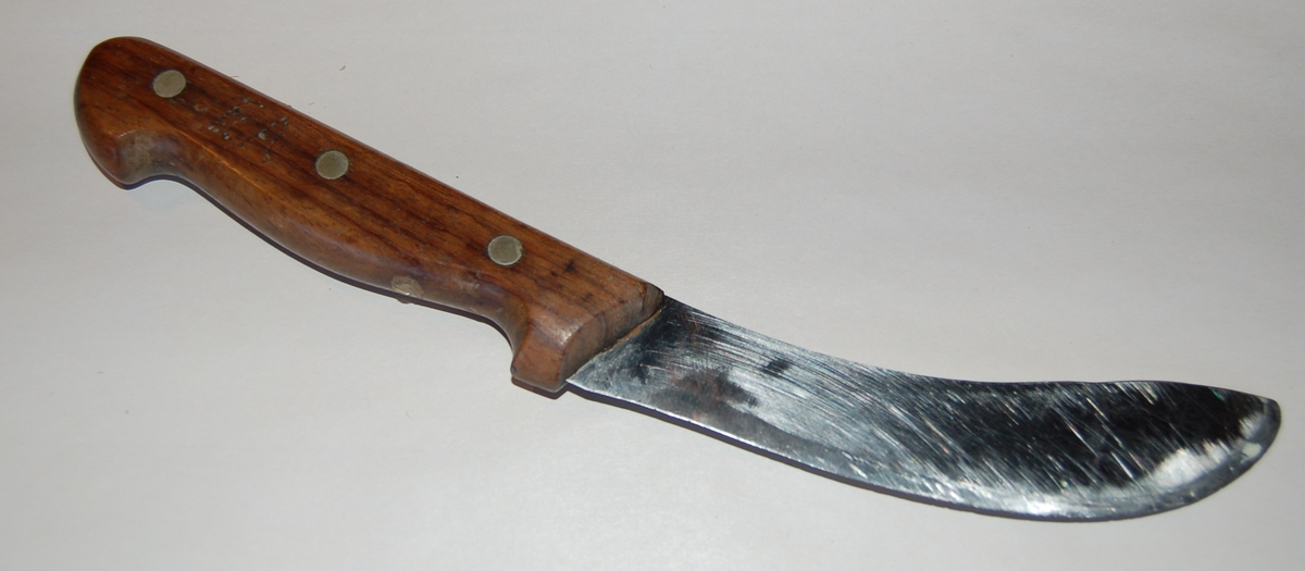 Svakt krummet breitt knivblad med skaft av tre. Skjeftet er festet til knivbladet med 3 messingnagler.