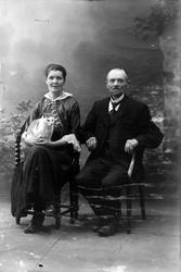 Studioportrett av en mann og kvinne med en katt på fanget.