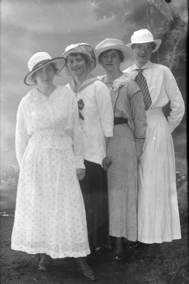 Studioportrett av fire kvinner med hvite hatter.
