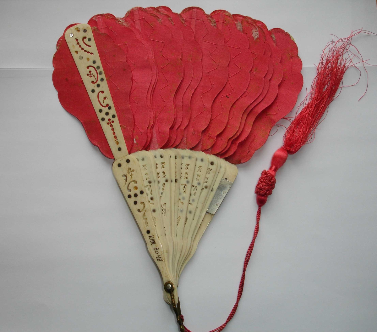 Håndvifte, hvit med røde vifteblad i tekstil, delvis formet som fjær, sannsynglivis fra midten - slutten av 1800.
