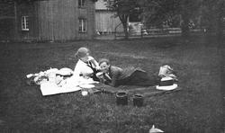 To damer tar en matbit på gressbakken. Aagot Olausssen til h