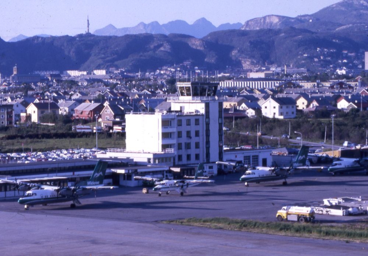 Flyplass/lufthavn. Flytårn/kontrolltårn med byen i bakgrunnen. Flere