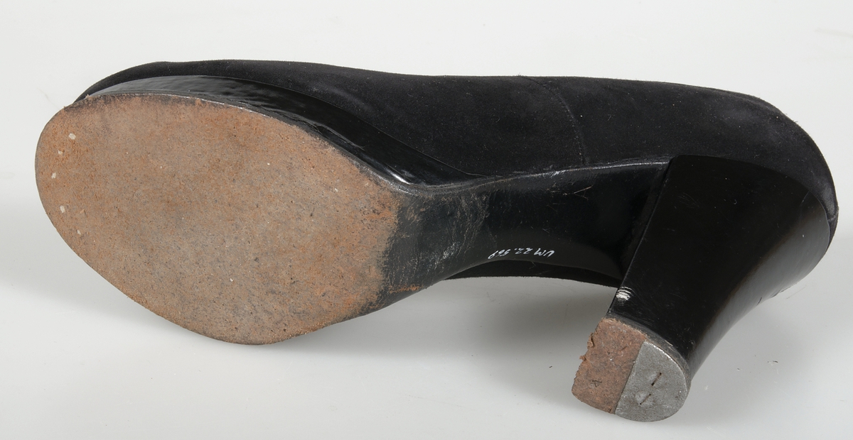 Damsko av svart mocka med platåsula och 10 cm hög klack. Modell: Ingeborg 2 A 81947, 4-. Storlek 4½ A. Under högerskons sula är årtalet 1942 skrivet.