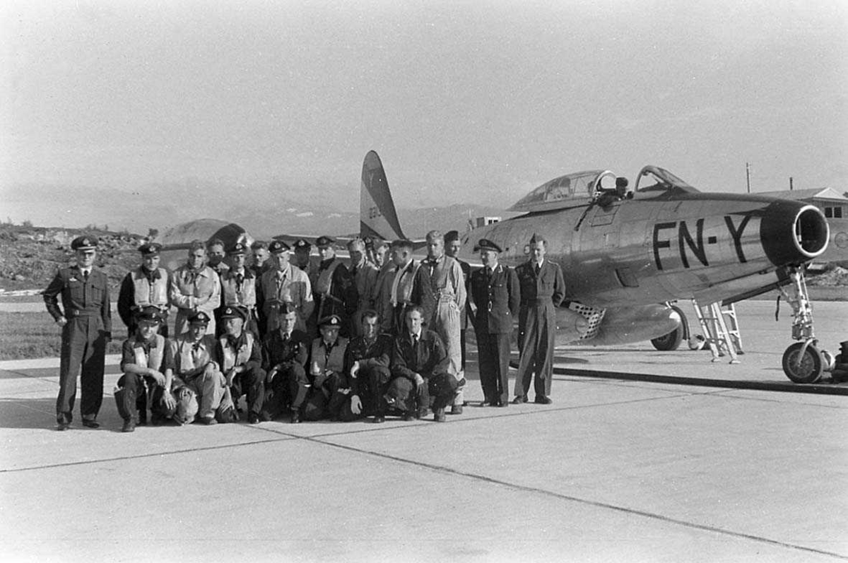 Gruppefoto av personell med jagerfly i bakgrunnen.