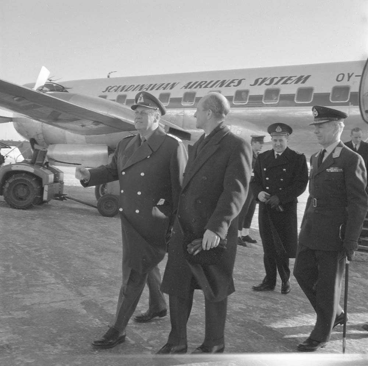 H.M. Kong Olav V besøker Bodø flystasjon før han drar videre til Bardufoss flystasjon. Flyet i bakgrunnen er en Convair Metropolitan 440.