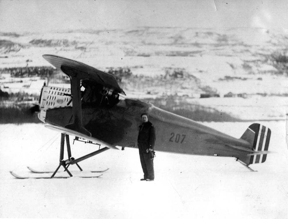 Ett fly på isen med flotører, lisensbygd FF 7 Hauk. En person står ved flyet.
