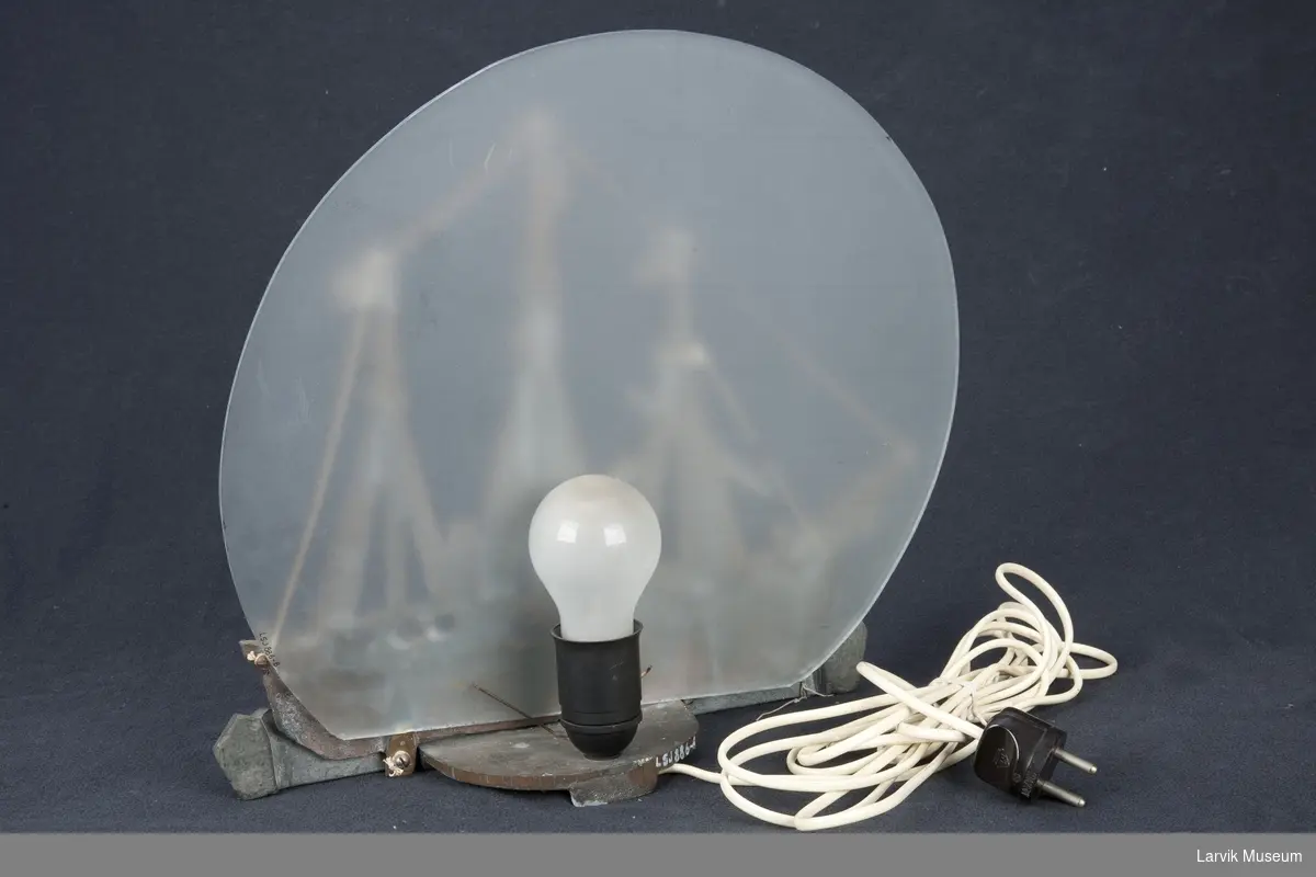 Støpt relieff av FRAM montert som lampe med børstet glass-bakgrunn, satt på hylle. Med ledning og kontakt
