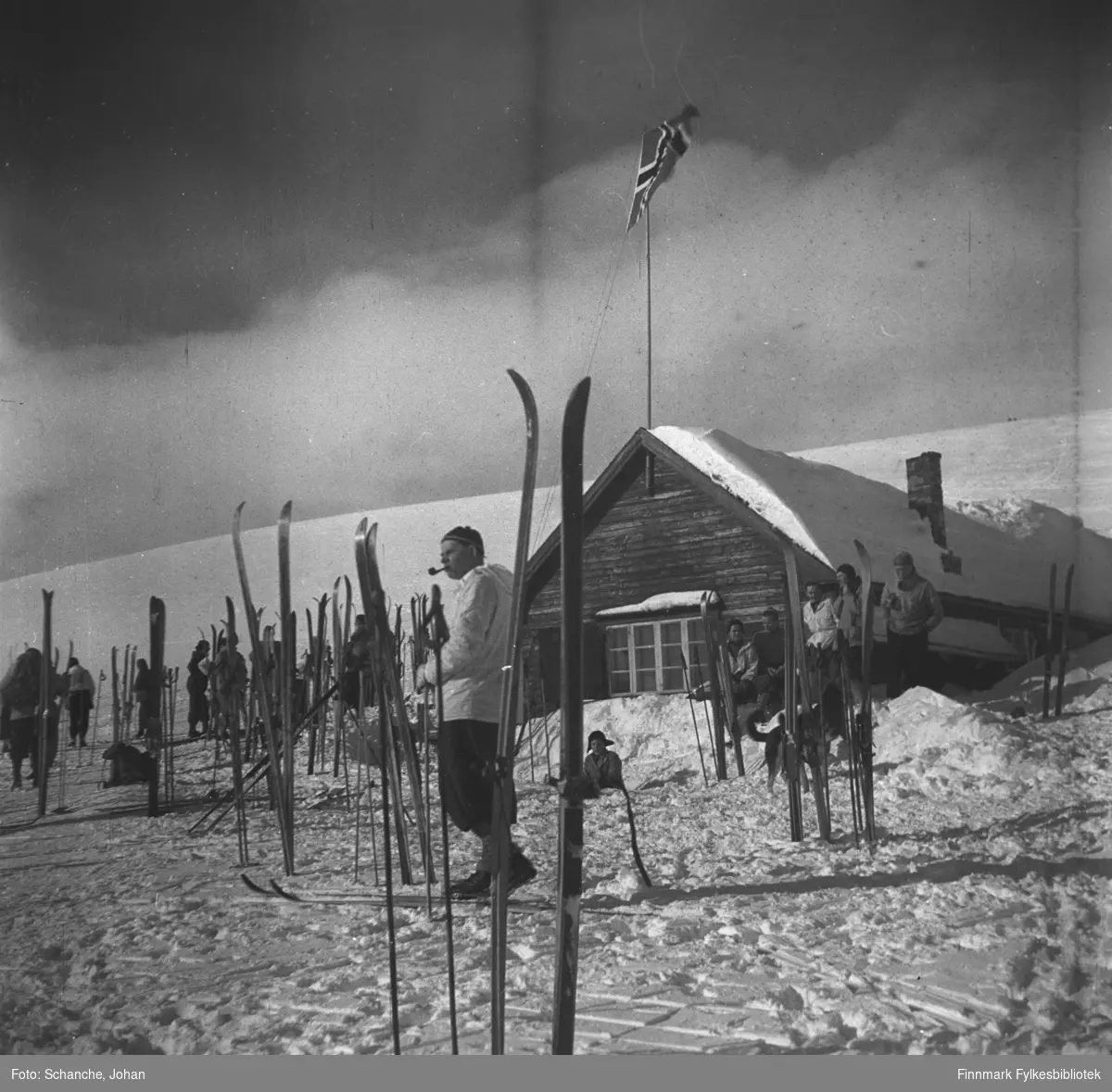 Vinikka skihytte fotografert en solig vårdag i 1946.  Flere skier står oppstillt på snøen rund hytta. Flaggen er heist opp og det går folk i anorakk bland skiene. Fremst på bildet står en mann og røyker pipa.
