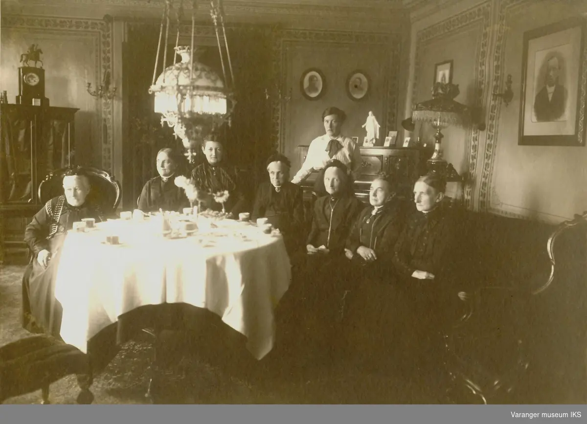 I stuen til Esbensengården i Vadsø sentrum. Ca 1890-1900. Rikka Dahl , Andrea Esbensen, Tora Dahl, ukjent, Ragna Esbensen, Agnete Esbensen, Marlene, Anna Rein