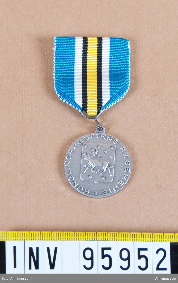 Norrbottens regementes (I 19) förtjänstmedalj i silver, 8:e storleken.

Band: blått med en gul rand på mitten åtföljd på vardera sidan av svart streck och en vit rand.