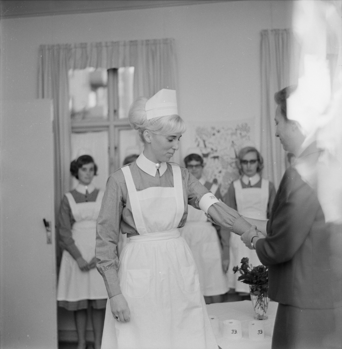 Nya barnsköterskor på Fackskolans daghem - barnavårdslärare Anna-Greta Nordin delar ut armbindel och betyg, Uppsala juli 1964
