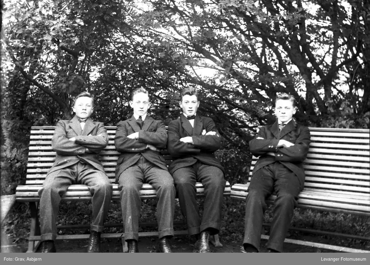 Gruppebilde, fire unge menn på benker i hage.