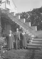 En mann og to kvinner ved trappen til Lyng Olsens hus i Park
