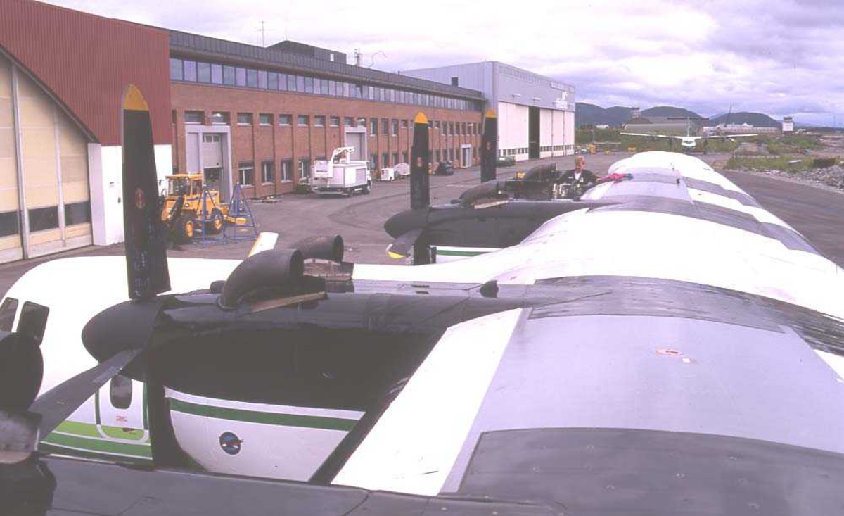 Lufthavn/flyplass. Bodø. Widerøes hangar. To personer. Ett fly, LN-WFE, DHC-7-102/ Dash7 fra Widerøe parkert. Flyteknikere inspiserer og tar vedlikehold.