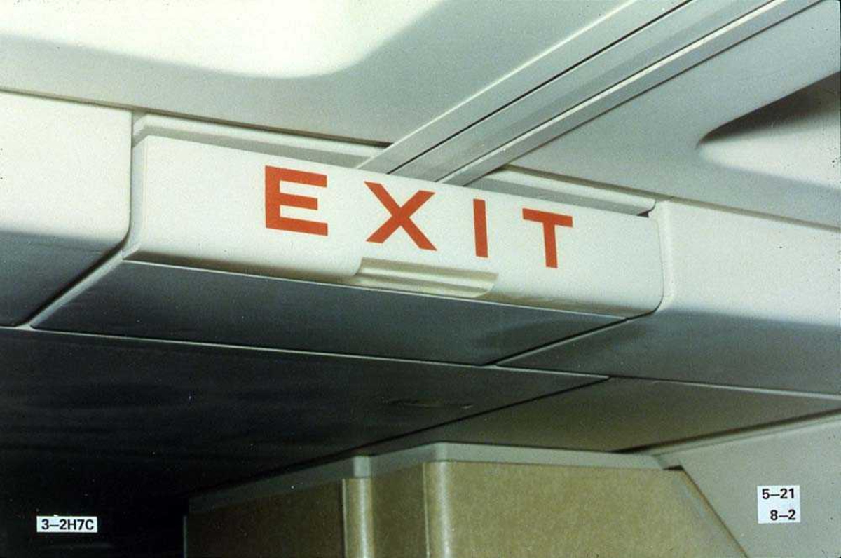 Detaljbilde av et exit-skilt inne i kabinen på ett fly, Boeing 737-200.