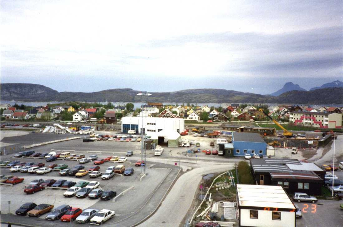 Lufthavn - flyplass. Bodø nye Lufthavn. Deler av den gamle flyterminalen med parkeringsplass og div. bygninger. I bakgrunn deler av bebyggelsen i vestbyen.