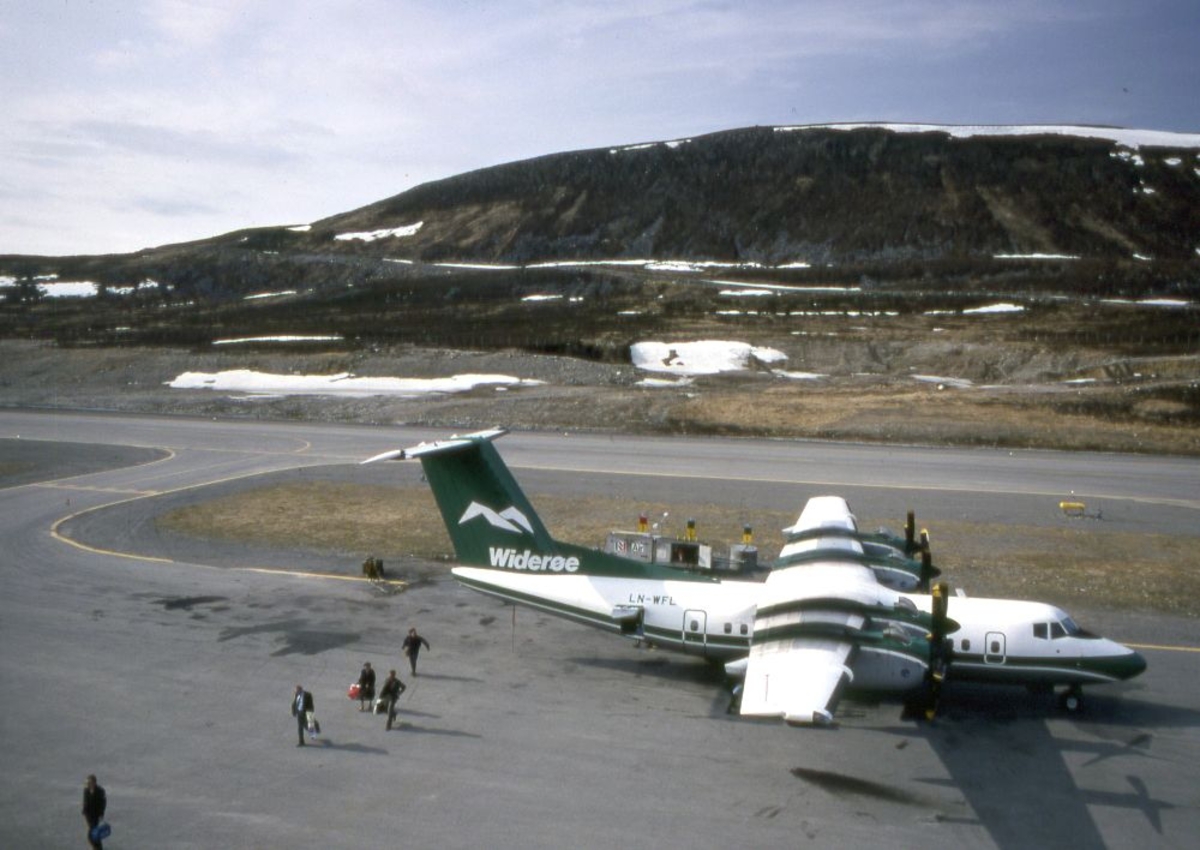Lufthavn (flyplass). Et fly, LN-WFL, DHC-7-102 Dash 7 fra Widerøe parkert. Flere passasjerer går fra flyet.