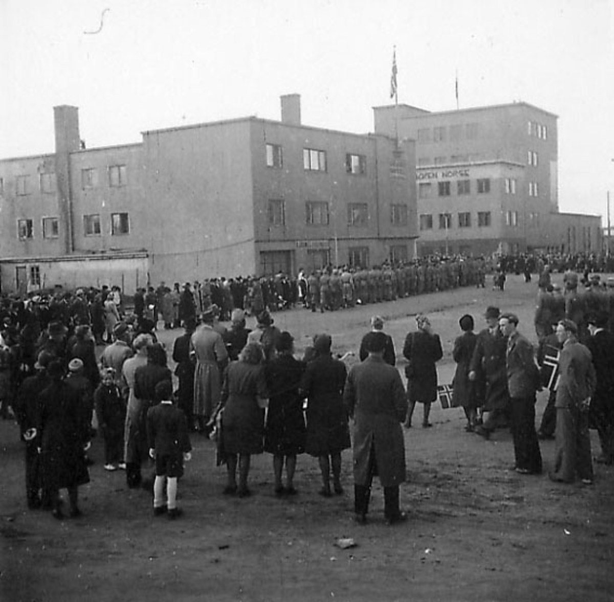Frigjøringsdagene i Bodø etter krigen  1945. Mange personer i gatene, sivile og militære. Grand Hotell bak.