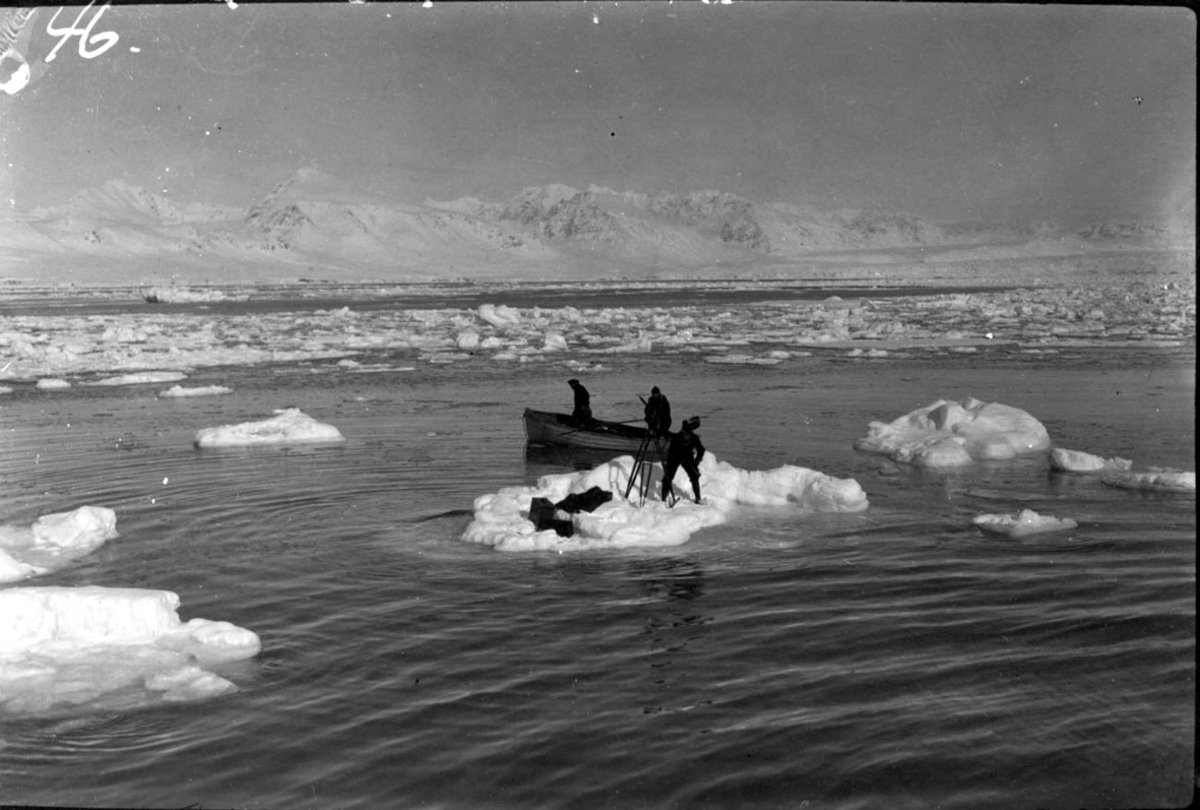 1 person, fotograf med utstyr på et lite isflak. En livbåt med 1 person ombord ved siden av