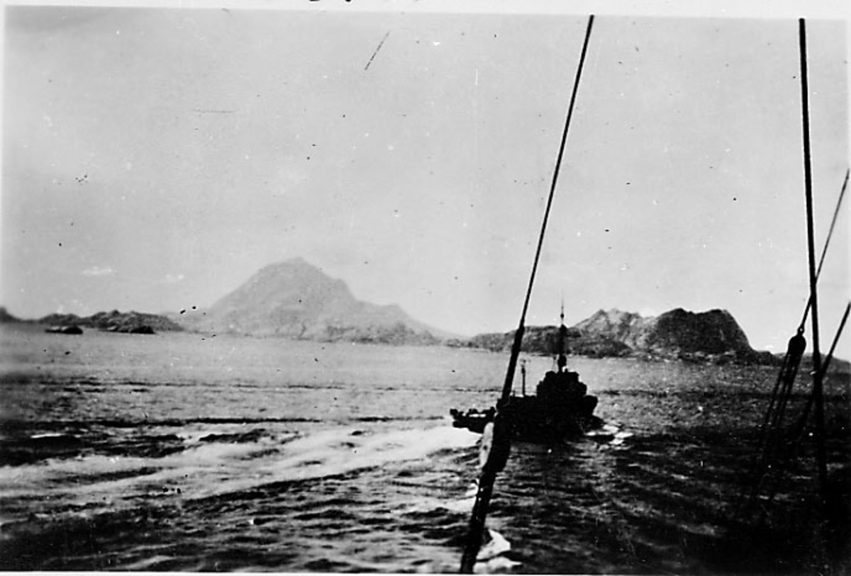 Fartøy i fart, land i bakgrunnen. Foto tatt fra annet fartøy. Narvik under 2. verdenskrig.