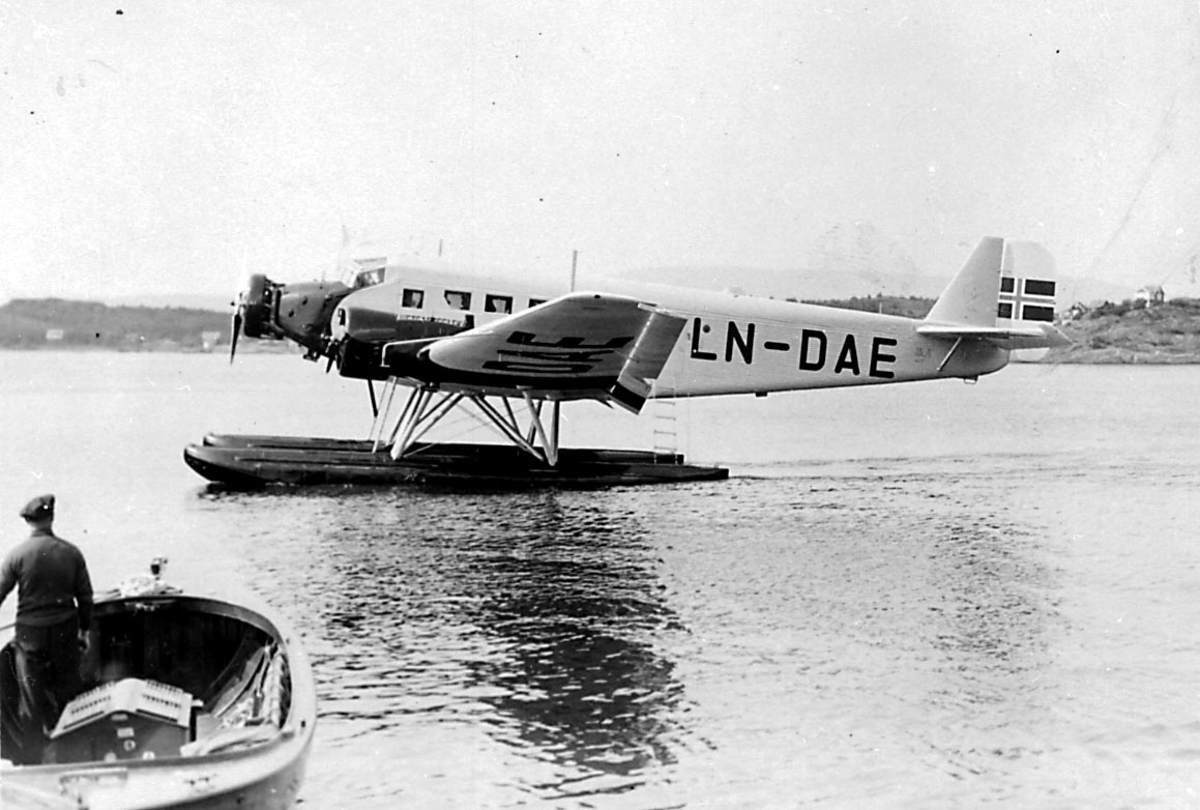 1 sjøflyfly på vannet, Junkers JU 52 3m ge, LN-DAE fra DNL Fred Olsen & Bergenske A/S. 1 person i 1 småbåt i forgrunnen.