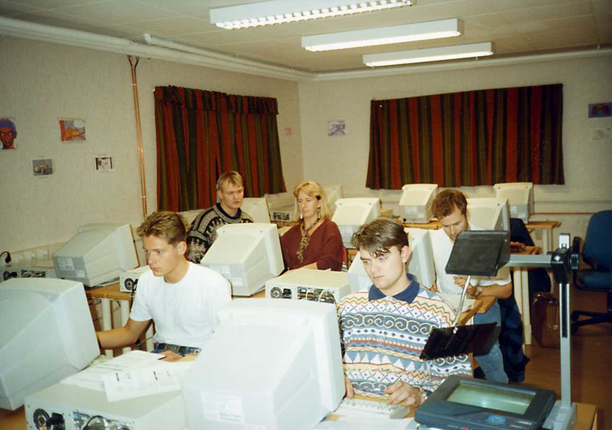 Gruppe. Fem personer ved dataskjermer i et klasserom.