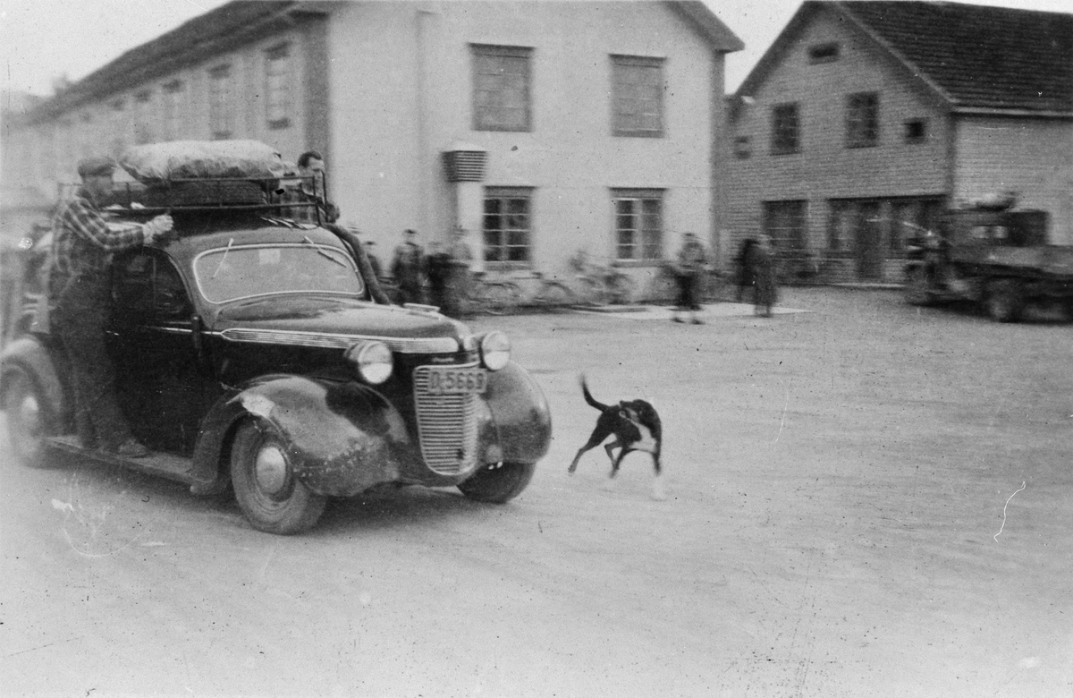 Bil med to menn på stigbrettet og last på taket. Leiret, Elverum. Frigjøringsdagene, mai 1945.