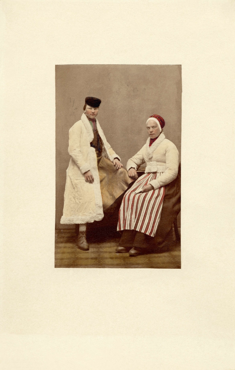 Ett par, kvinnan i folkdräkt och vit kort jacka, mannen i en vit långrock