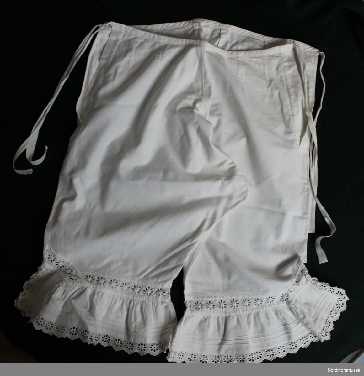 Knelang underbukse for dame. Maskinsøm i bomull. Knyting i begge sider i livet. Blonder i avslutning ved kneet.