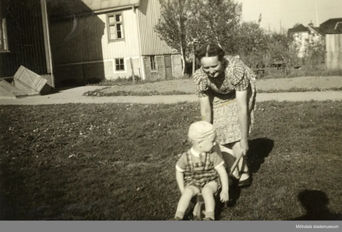 Reino Svensson (född: 1939, storebror till givaren) får åka skottkärra då mamman kör honom på gräsmattan hemma på Solhemsgatan i Mölndal år 1941. Relaterat motiv: 2007_0448.
