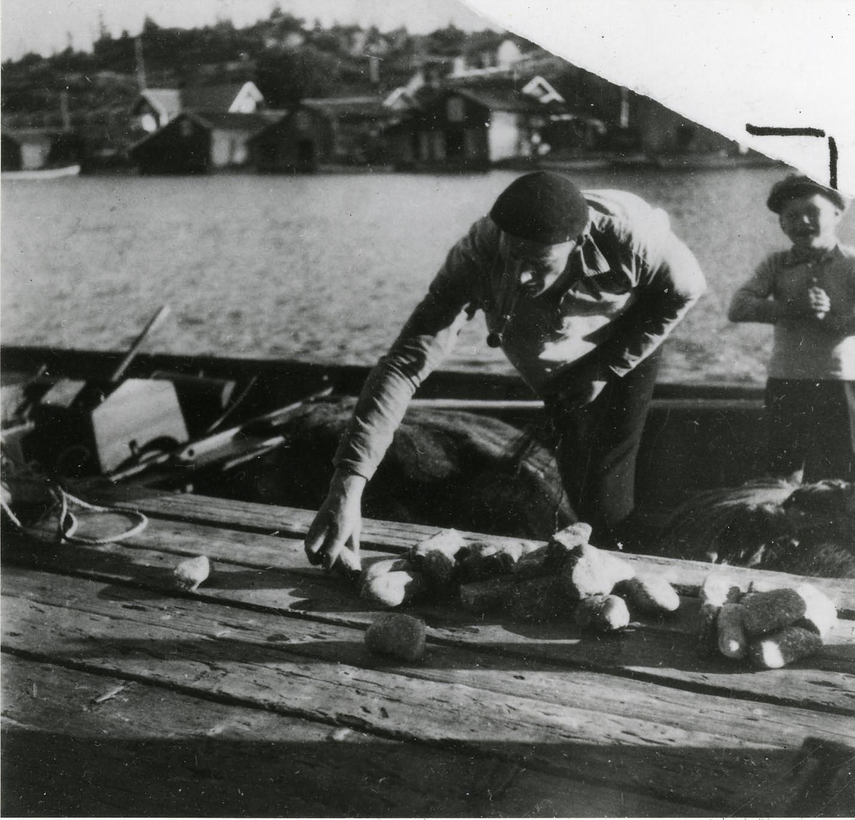 Ångermanland, Trysunda. Fiskaren Leonard Lundgren stenar (dvs. förser skötarna med stensänken) skötar före utfärden till fiskeplatsen.
Fotot från början av 1930-talet.