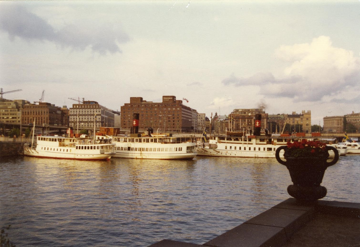 Foto i färg visande en del av Strömma Kanalbolagets fartyg vid kaj Klara Mälarstrand, Stockholm, 1974.