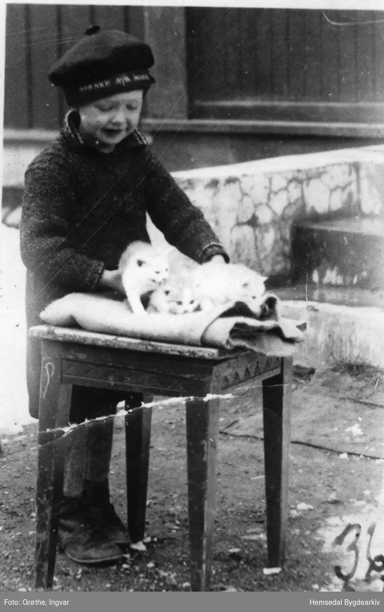 Johnny Grøthe steller ut kattungar utanfor barndomsheimen sin, Fagerheim, 67.37, i Hemsedal i 1936
