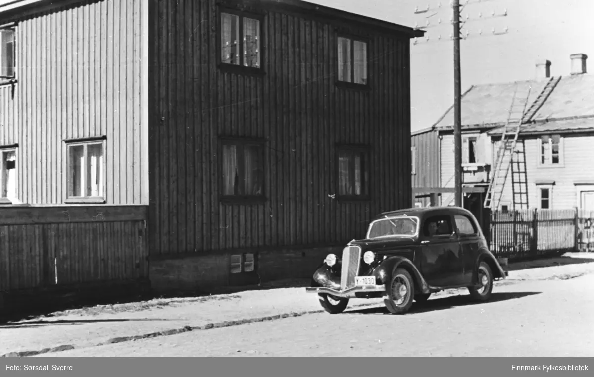 Bildet av huset til Paulsen i Vardø fra 1936. Foran huset står en bil, en Ford Junior deluxe 1935, og det går et gjerde rundt huset. Sørsdals første bolig. Leide 1-2 rom hos Kristian Paulsen som nygift. Bilen tilhører Birger Bjerkeng, f.1905, husflidsskolebestyrer i Vardø fra 1932. Denne bilen ble kjørt nordover for ham i 1935, av Sverre Sørsdal. Den samme bilen er med på flere bilder i Sørdals bildeserie.