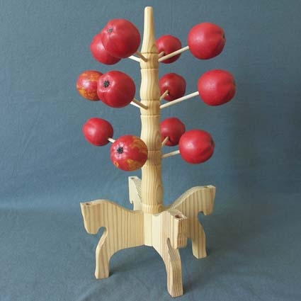 Ljusstake bestående av femton röda äpplen, tolv pinnar att fästa äpplen på, en mittpinne och en fot bestående av fyra hästformade delar.