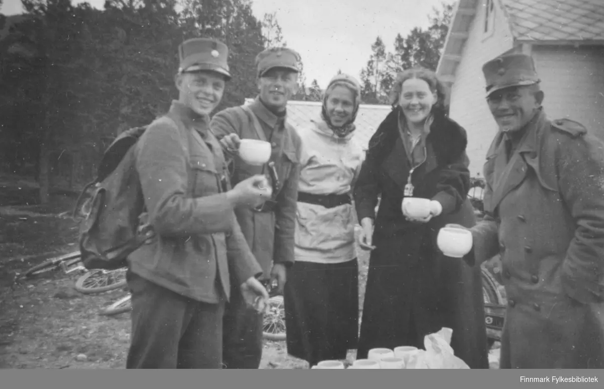 Soldater og sykepleiere drikker kaffe utendørs. I bakgrunnen ligger sykler slengt på bakken. Bildet kan være tatt på en matstasjon under utmarsj