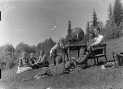 Gruppe mennesker (familie) ute på jordet med grammofon.