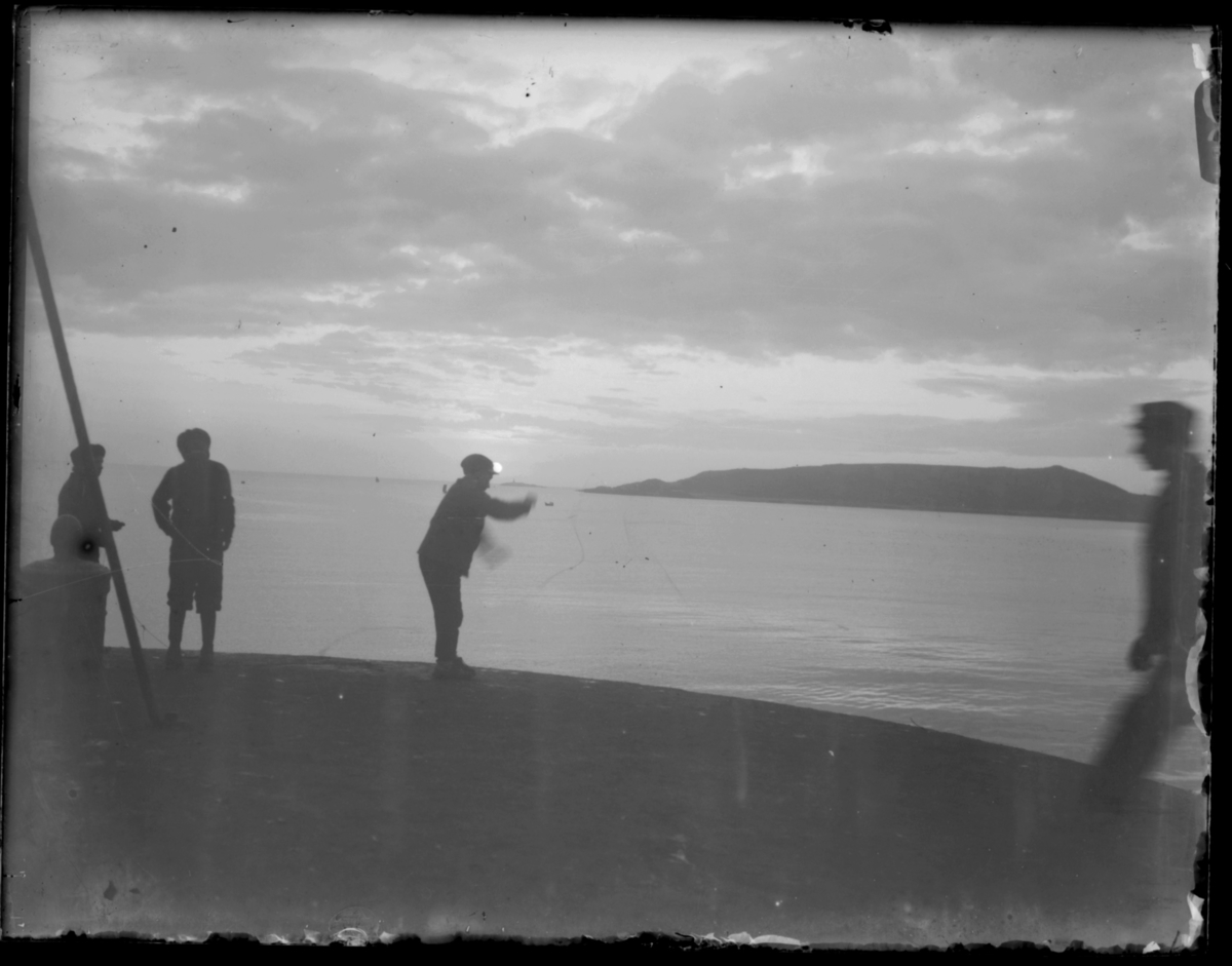 Noen gutter står på kaia i Vardø og fisker med snøre i midnattsola