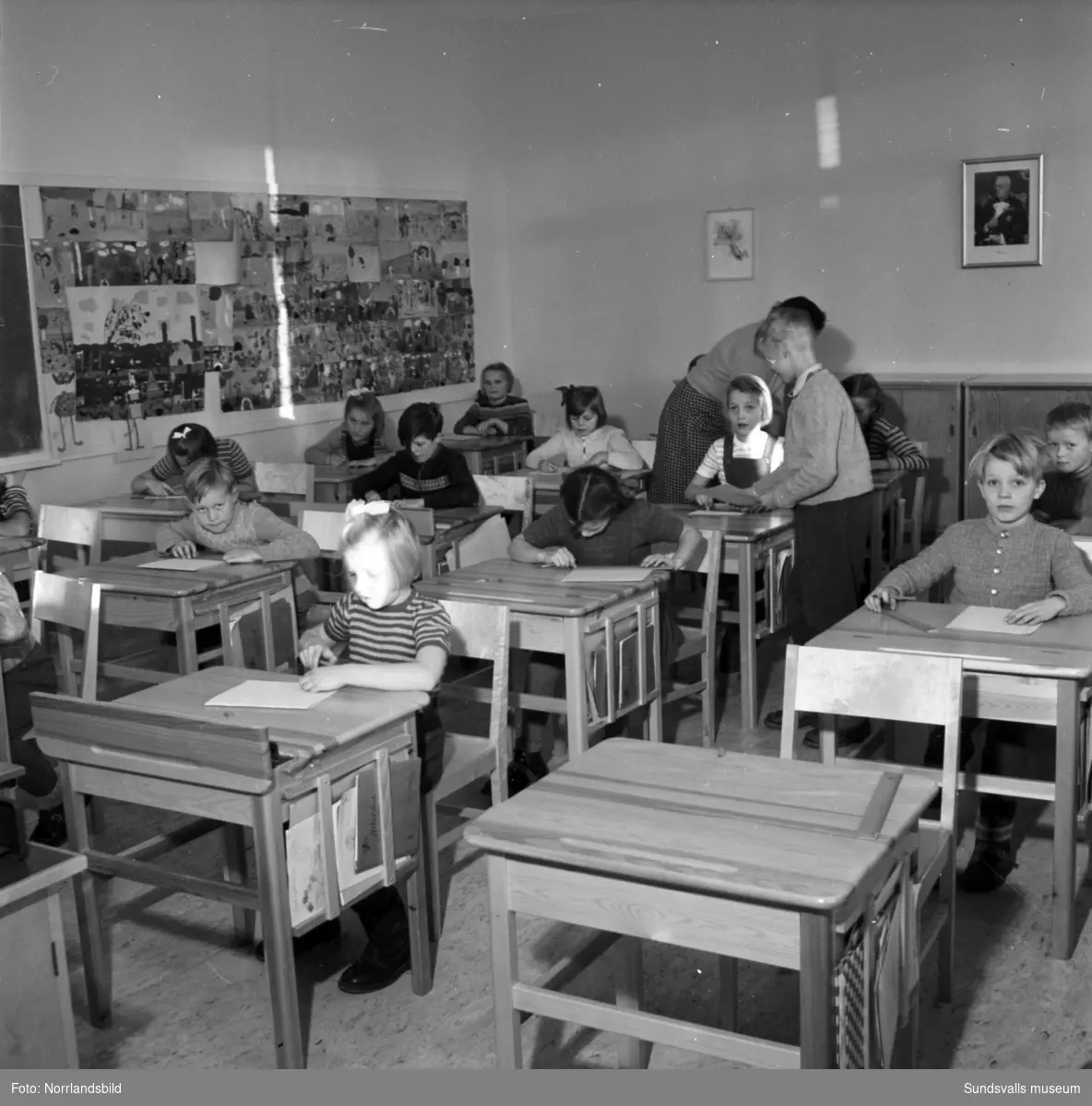 Reportagebilder från Stöde skola 1950. Exteriör, interiör, lektioner i klassrummen, rastlek, elever, personal, lärarrum, affischförråd samt en del andra hus i omgivningen.