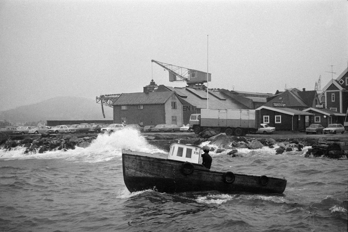 Parti av Harstad havn, med kullkrane i bakgrunnen og fløttmannsbåten i forgrunnen.