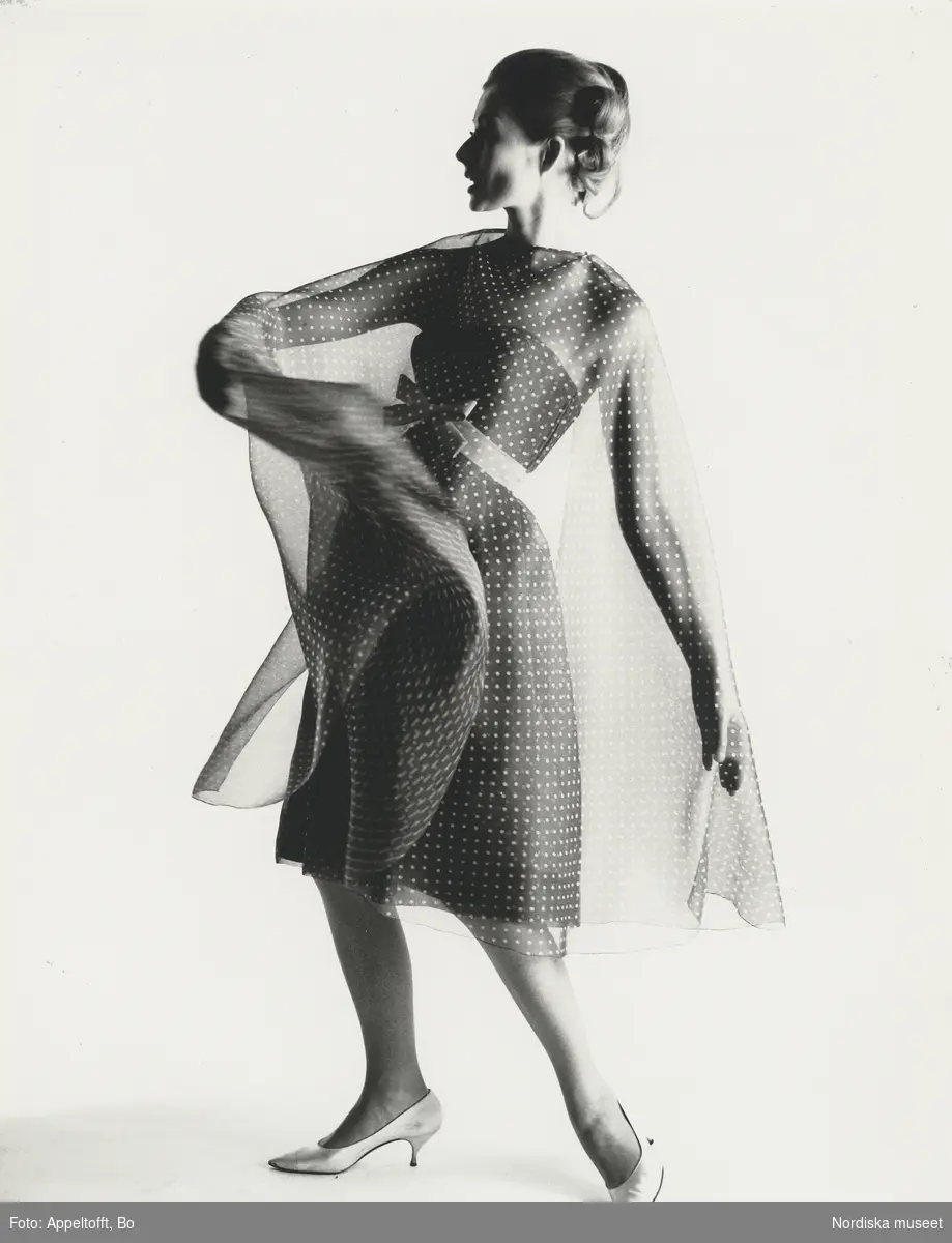 Modell i klänning med transparent, prickig cape. NK:s Franska, från J. Patou. Vår.