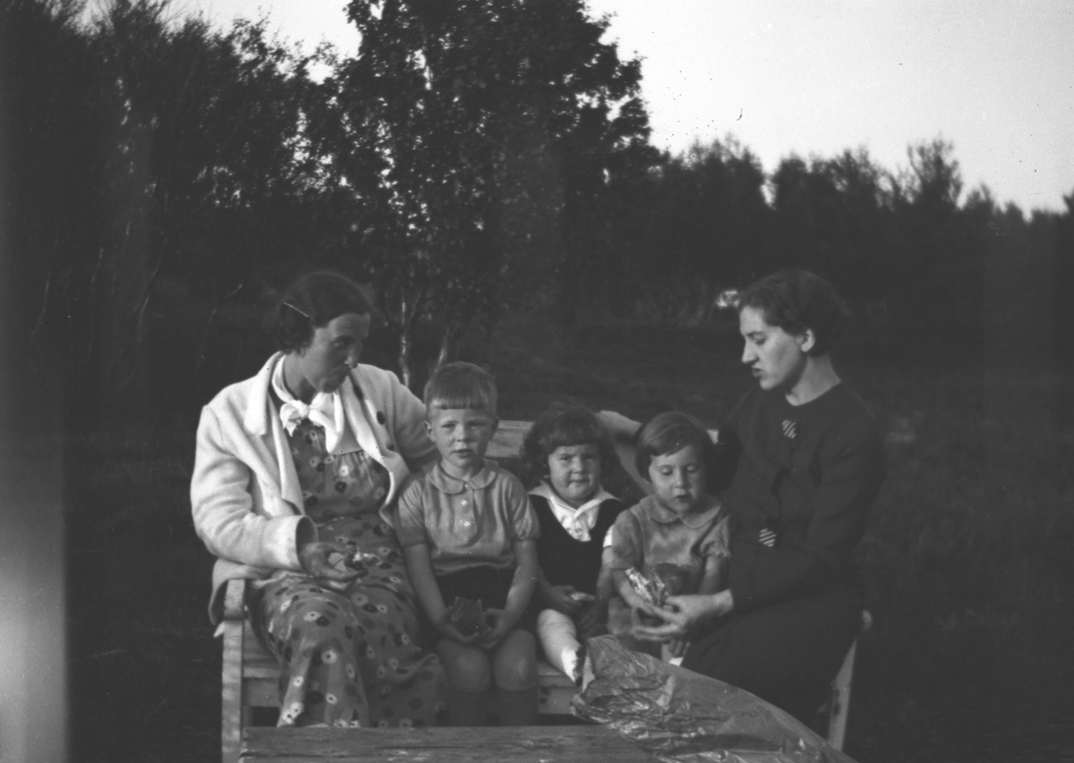 To kvinner og tre barn sitter på en benk. De er fra venstre: Frida Hauge, Tor Hauge, Kjell Persen, Bergljot Persen og Johanna Persen. Stedet er ukjent, men det kan være i Vadsø.