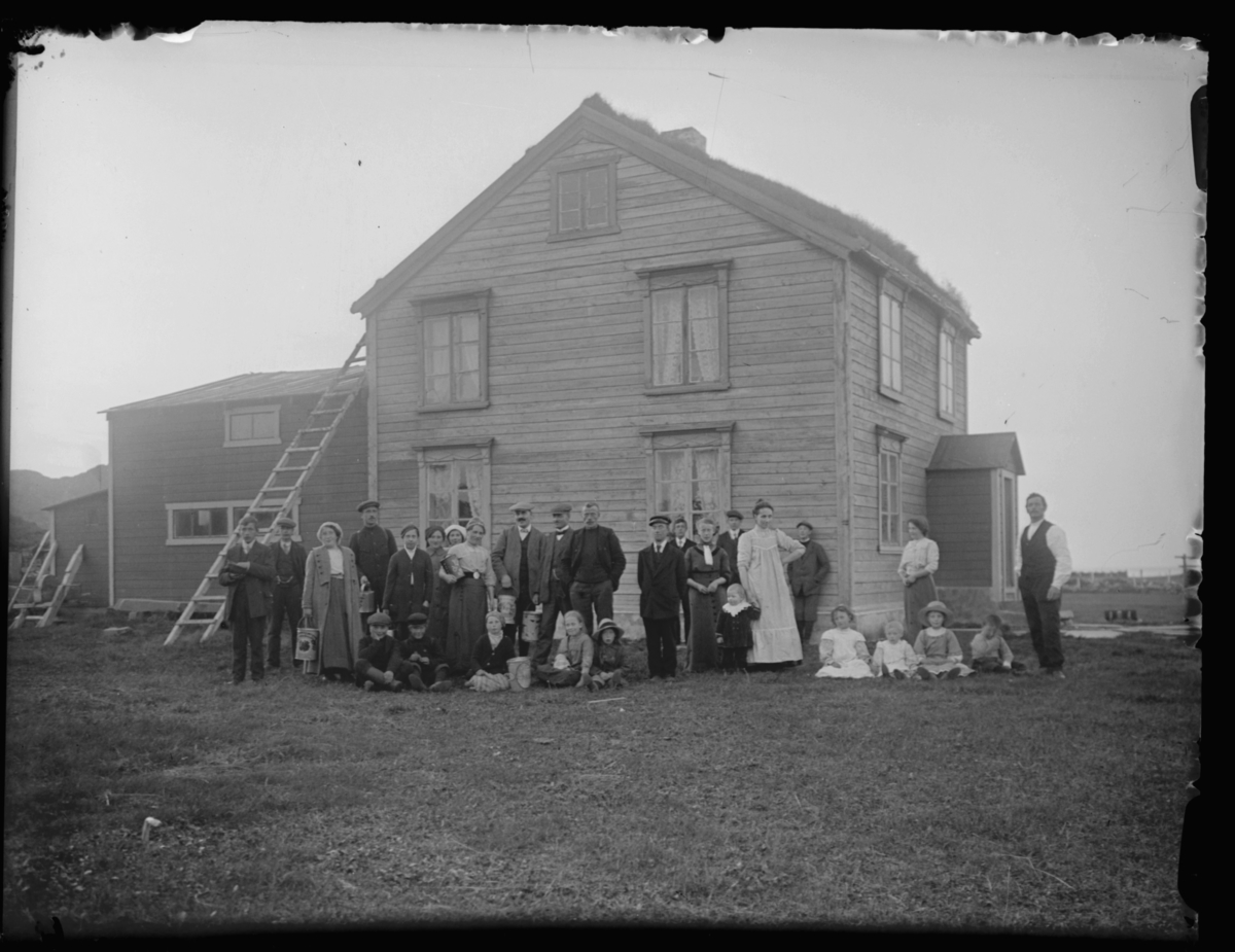 En gruppe mennesker fotografert utenfor huset til Hans Christian Enoksen (1843-1901) i Løkvika på Smelror, Vardø kommune.